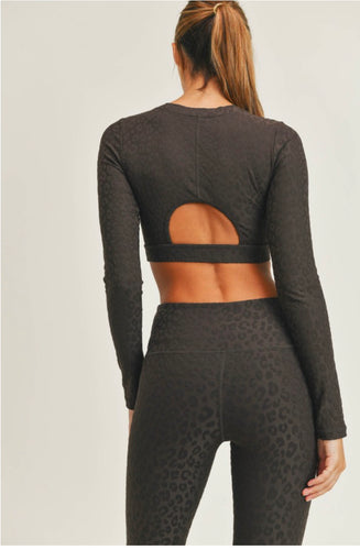 Backside of Women wearing peekaboo back long sleeve crop top for workout or active wear.